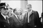 dr. martin luther king talking to malcolm x outside with police officer on left